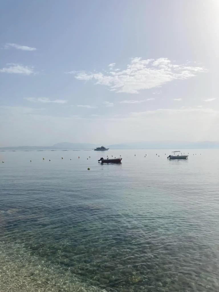 How do I travel from Corfu Airport (CFU) to Kassiopi without a car?- blue water with boats in the distance