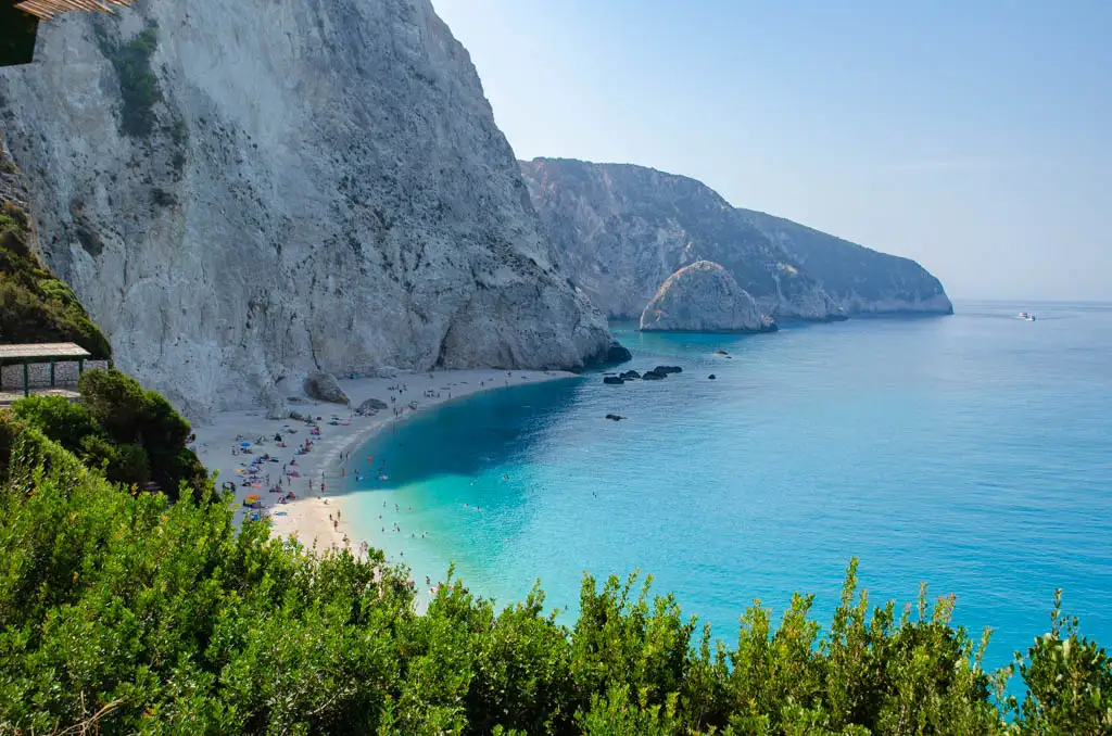 Driving From Athens to Lefkada Greece- blue sea and golden beach, underneath cliffs, green shrubs Lefkada in Greece
