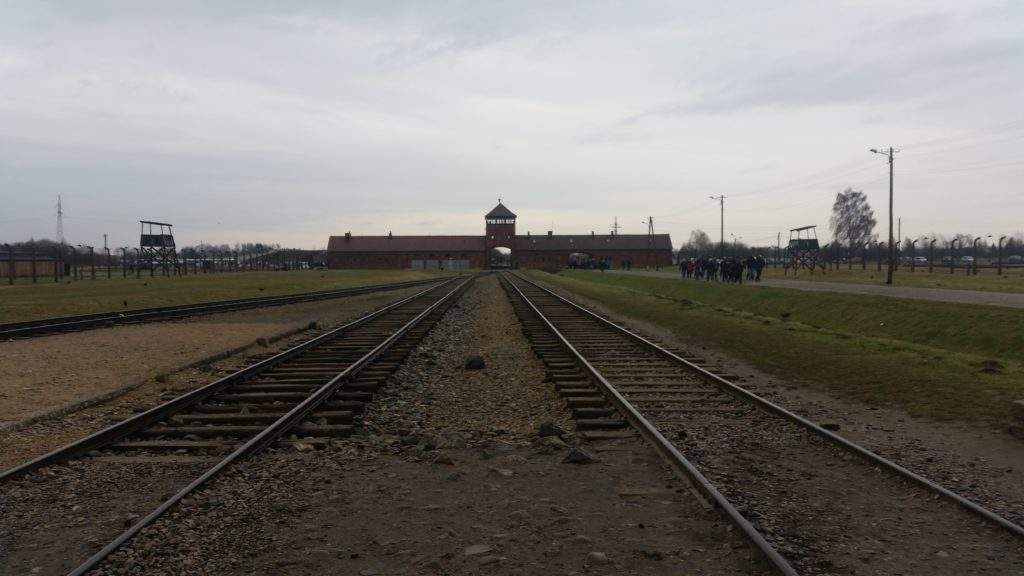 Auschwitz tour from Krakow- train tracks, large building,grass, Poland