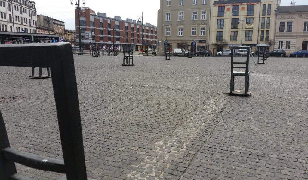 Krakow Auschwitz and Jewish Quater And Ghetto Tour, Poland Holocaust Tour- chairs, cobbled streets, tall buildings in Krakow