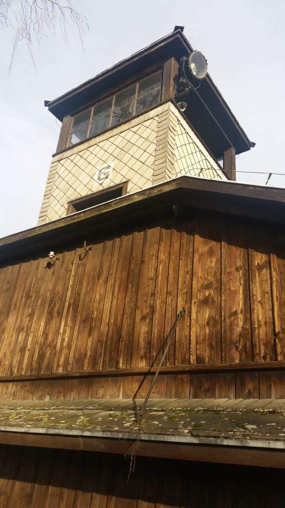 The Best tours of Auschwitz from Krakow- tall look out tower, brown wood, barbed wire