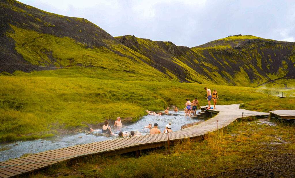 Reykjadalur hot springs in the green hills of southern Iceland have great access because of the wood walkway surrounding it and the natural shallow pool is a great spot when driving from reykjavik to vik