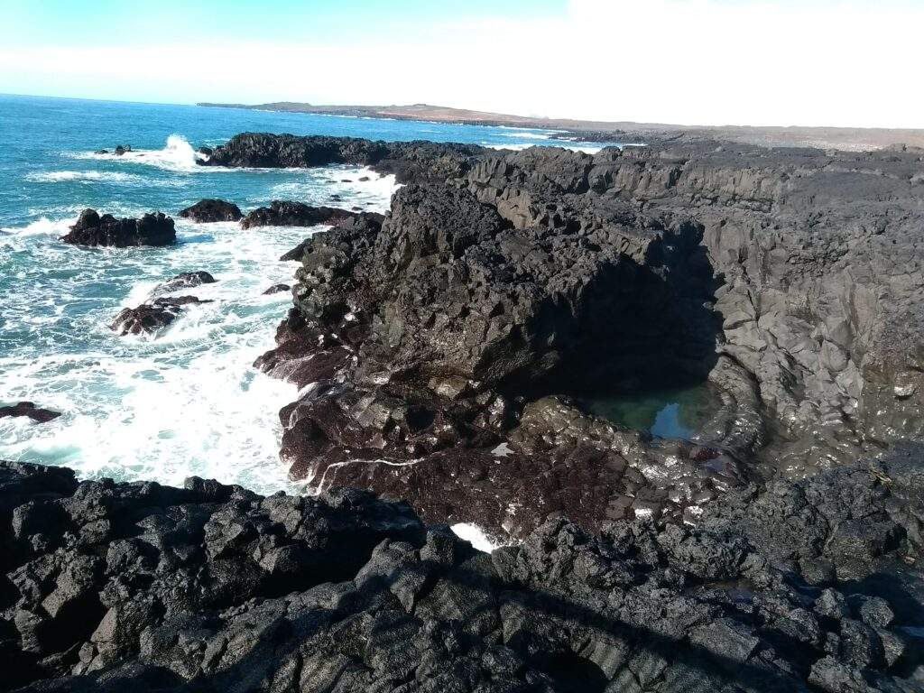 black sand beach has black cliffs and blue waters around it
