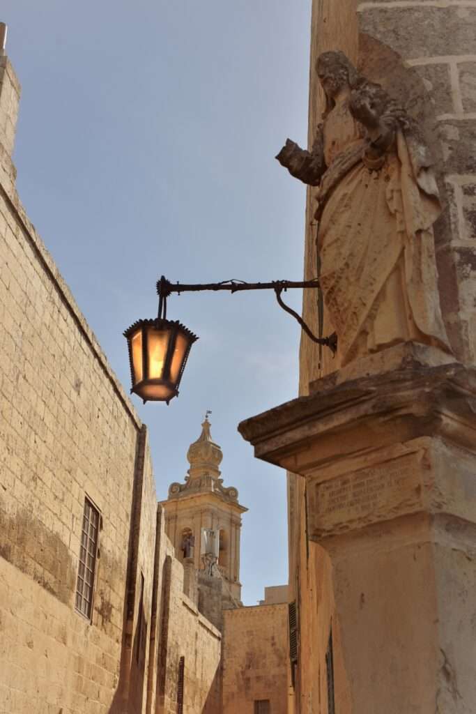 Mdina and Rabat walking tour in Malta- street corner, religious statue, sand coloured building, old fashioned black street light