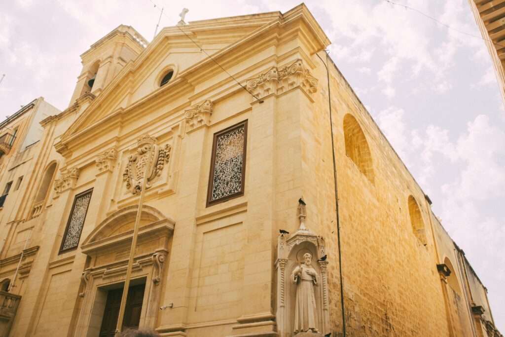 Walking tours to book in Valletta, Malta will see a lot of old sand coloured buildings with religious symbols and carvings on them