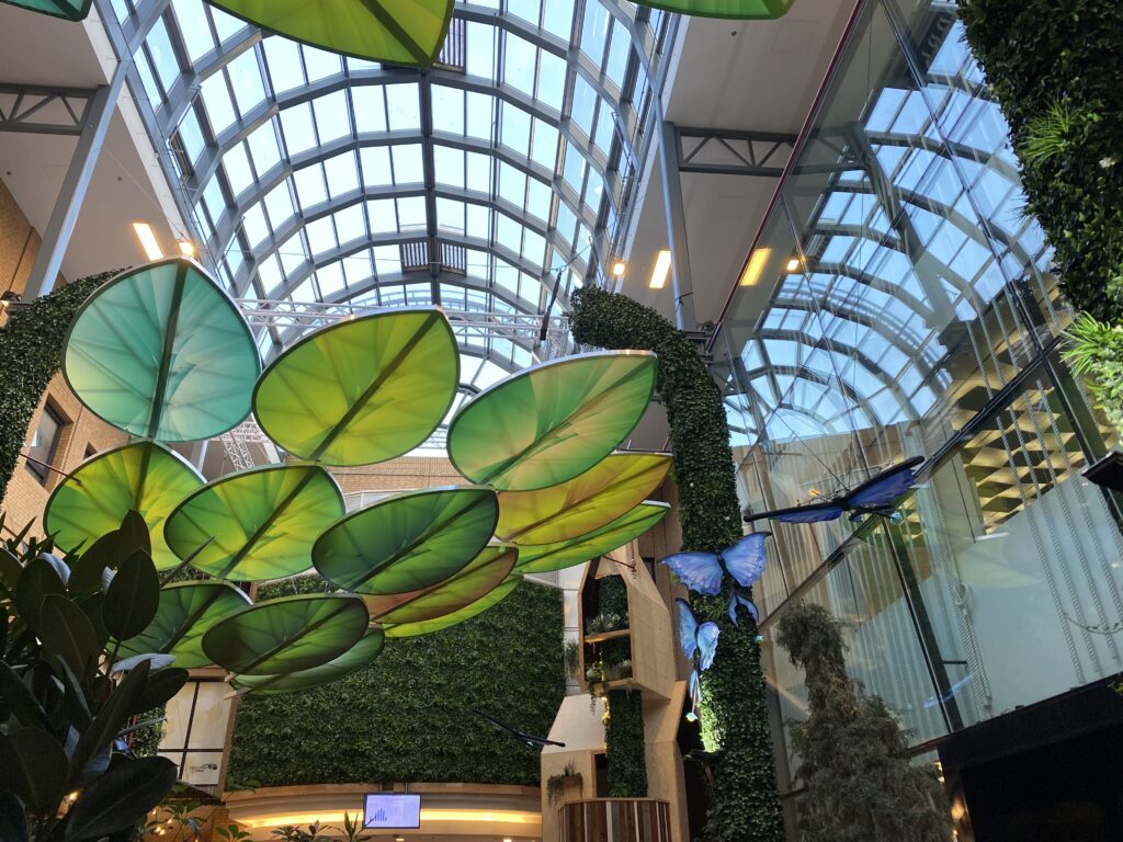 Huge plastic green leaves and blue butterflies can be found below the glass cellings of Eindhoven shopping centre