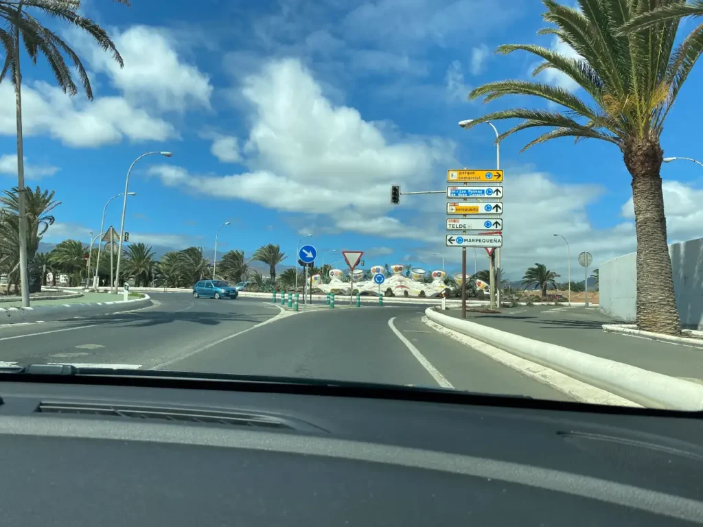 a long highway in Gran Canaria with palm trees on side and looking straight on to the bright blue skies